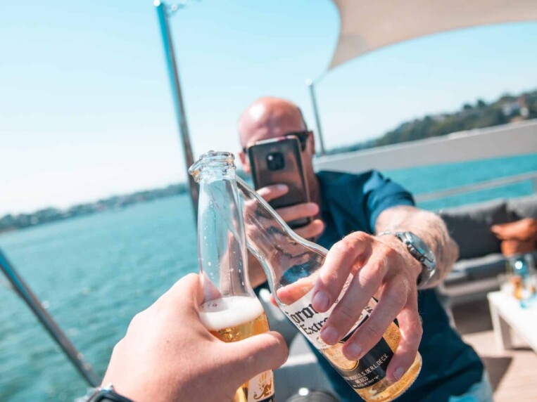amici che brindano con birra in bottiglia su una barca